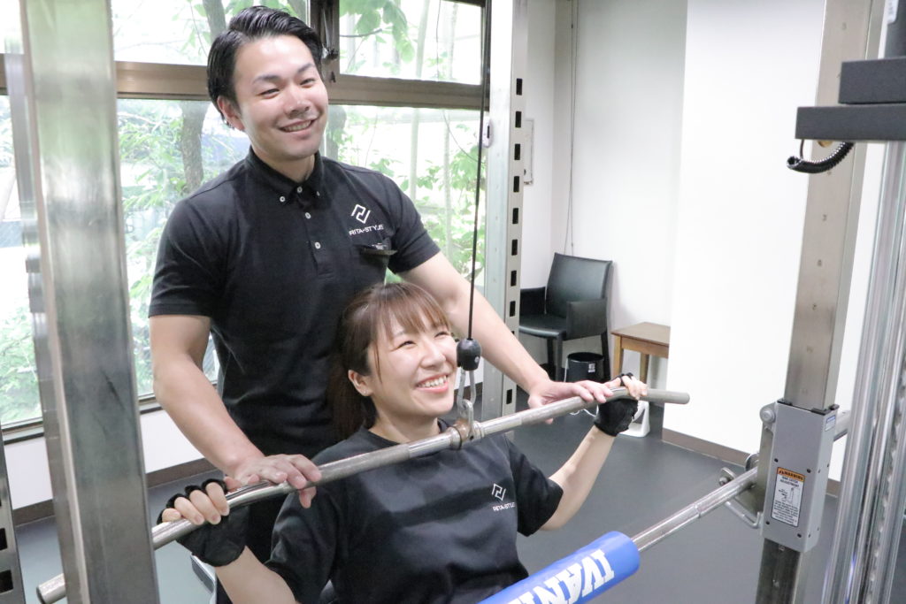 パーソナルジムでトレーナーと一緒にトレーニングをする女性